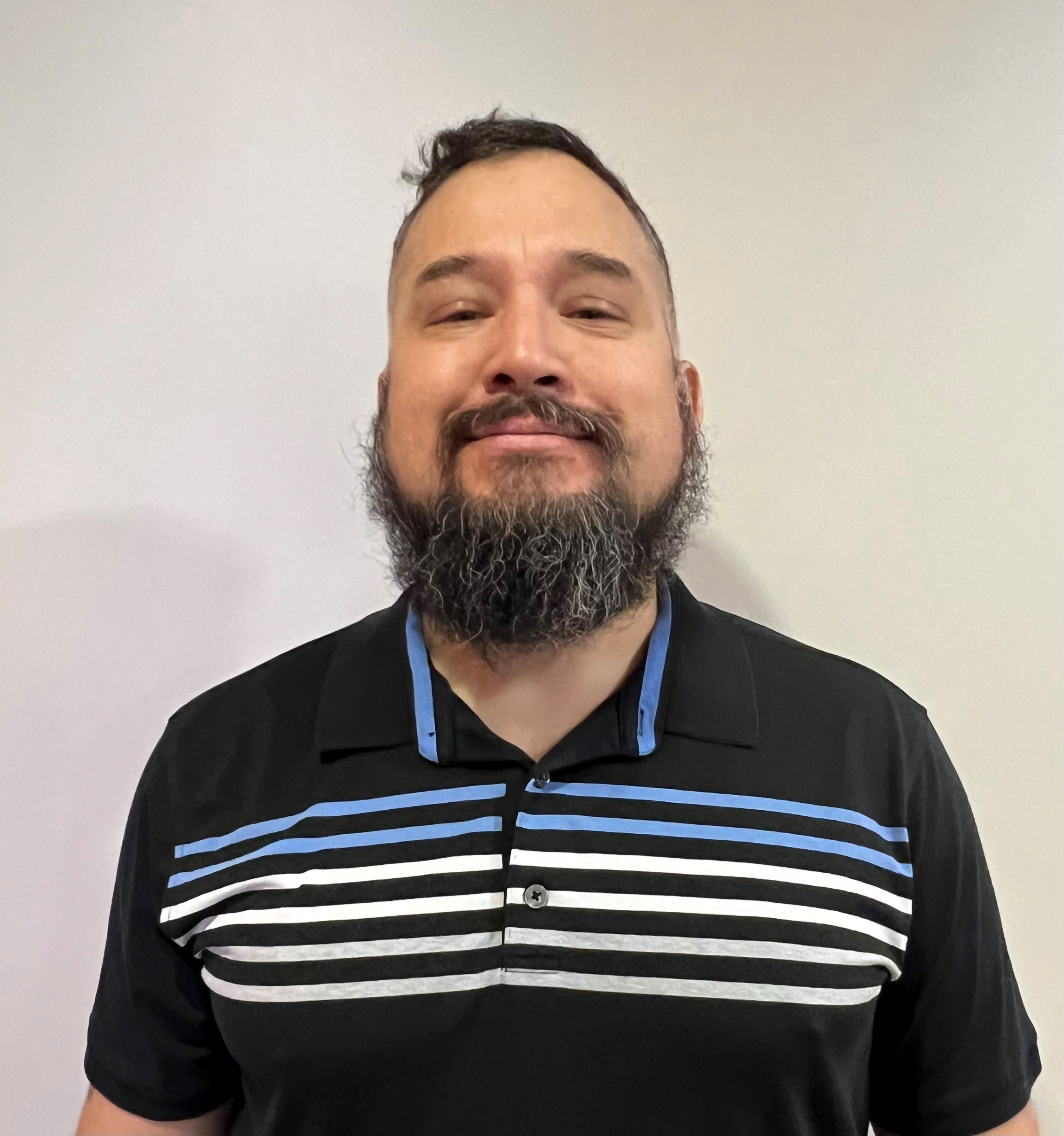 portrait of Brent Augustine. An Indigenous man smiling with a beard and a stripped golf shirt.